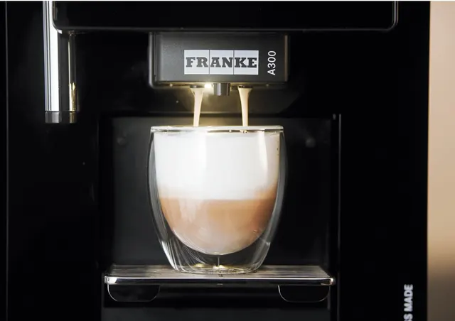 Franke A300, kava su pienu teka į stiklinę, vaizdas iš arti